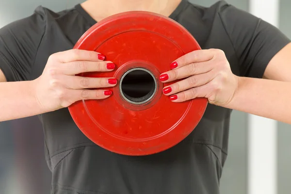 Feminino vermelho pregado e braços fortes segurar peso — Fotografia de Stock