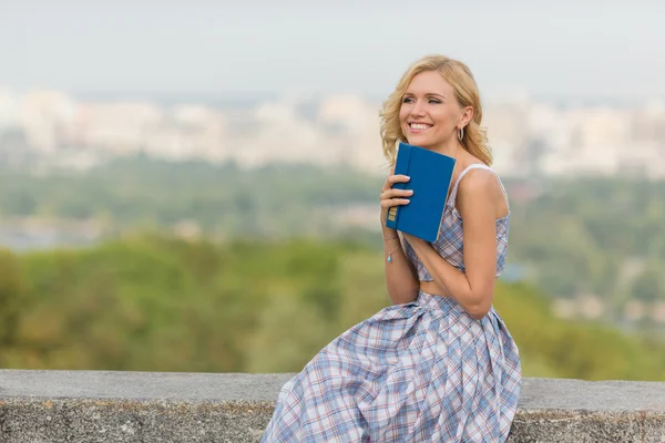 Sorridente signora con un libro all'aperto — Foto Stock