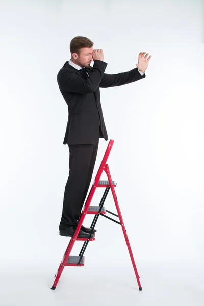 Empresário na escada usando telescópio — Fotografia de Stock