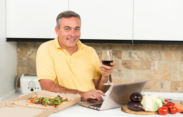 Hombre maduro con portátil en la cocina — Foto de Stock