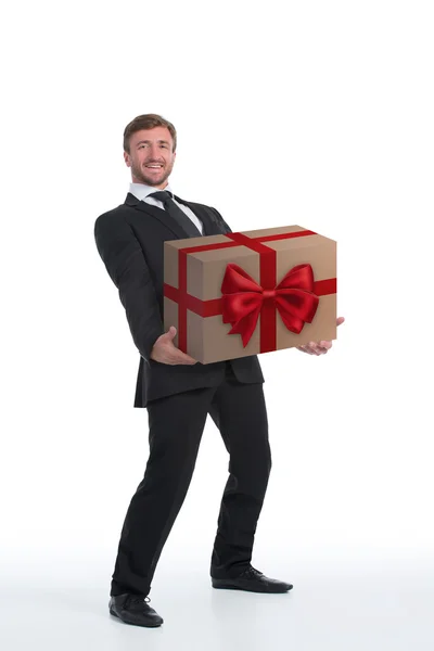 Smiling businessman carrying heavy present — Stock Photo, Image