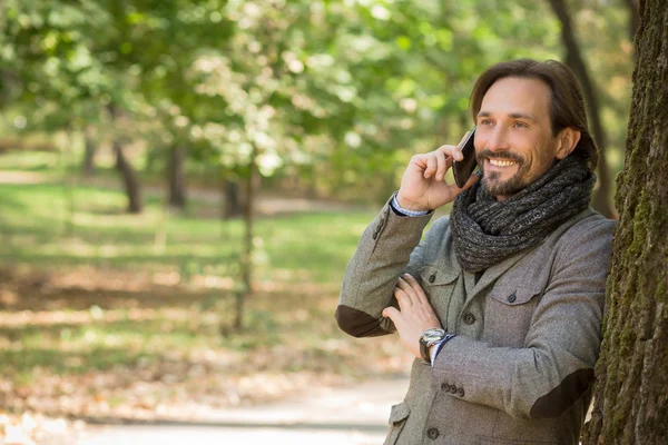 Handsome middle-aged man talking over mobile phone in the park — Stock fotografie