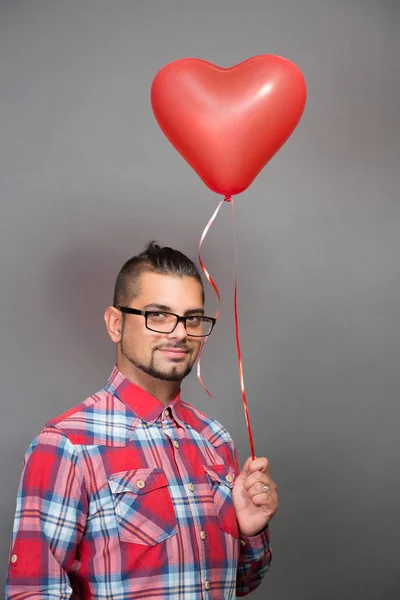 Bonito hipster homem com balão de coração vermelho no estúdio — Fotografia de Stock