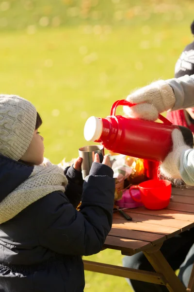 A little kid holding a cup while her mother pouring tea — Stock Fotó