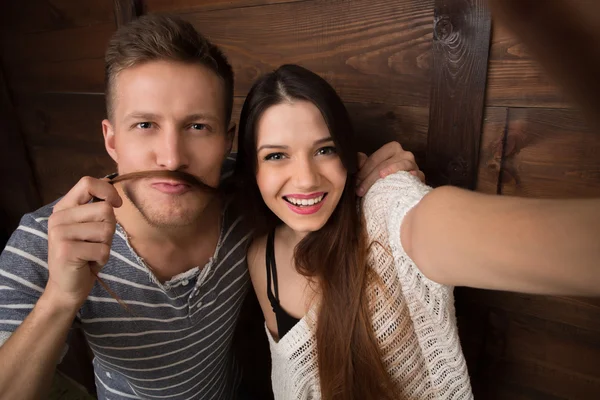 Pareja feliz haciendo selfies aislados sobre fondo de madera —  Fotos de Stock