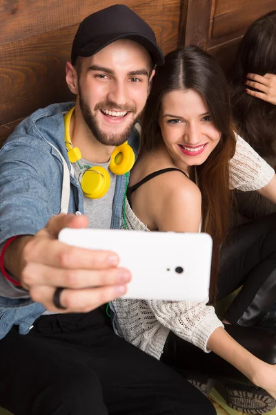 Glückliche Freunde machen Selfie, während sie auf dem Boden sitzen Stockfoto