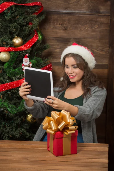 Beautiful girl making selfies on tablet PC near New Year tree — Stock Photo, Image