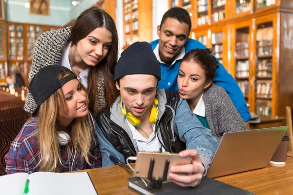 Estudantes fazendo selfies na biblioteca — Fotografia de Stock