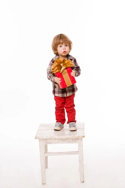 Beautiful baby with a present on stool — ストック写真