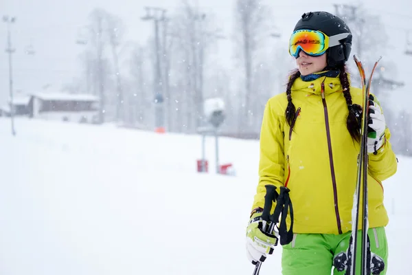 Vrouwelijke skiër permanent met een hemel in de ene hand op achtergrond prachtige berglandschap — Stockfoto