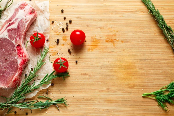 Kousky surového masa s rozmarýnem a rajčaty. — Stock fotografie