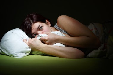 Young woman in bed with eyes opened suffering insomnia. Sleeping concept and nightmare issues