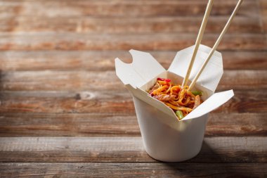 Domuz eti ve sebzeli erişte, ahşap masadaki paket kutusunda.