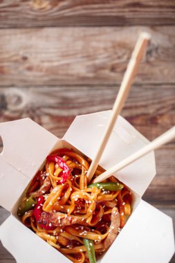 Domuz eti ve sebzeli erişte, ahşap masadaki paket kutusunda.