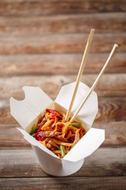 Domuz eti ve sebzeli erişte, ahşap masadaki paket kutusunda.