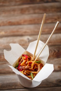 Domuz eti ve sebzeli erişte, ahşap masadaki paket kutusunda.