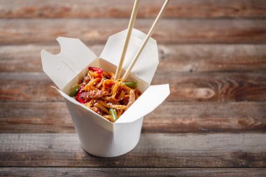 Domuz eti ve sebzeli erişte, ahşap masadaki paket kutusunda.