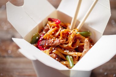 Domuz eti ve sebzeli erişte, ahşap masadaki paket kutusunda.