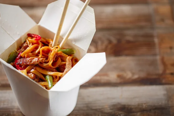 Nudeln mit Schweinefleisch und Gemüse in Take-Out-Box auf Holztisch — Stockfoto