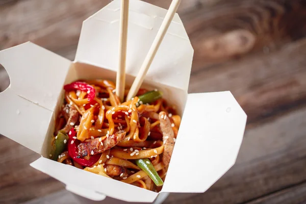 Nudeln mit Schweinefleisch und Gemüse in Take-Out-Box auf Holztisch — Stockfoto