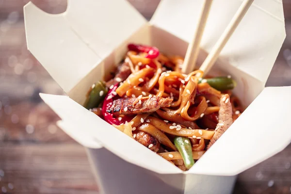 Nudeln mit Schweinefleisch und Gemüse in Take-Out-Box auf Holztisch — Stockfoto