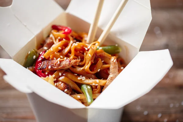 Nudlar med fläsk och grönsaker i take-out box på träbord — Stockfoto