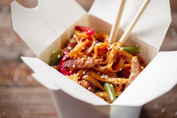 Nudlar med fläsk och grönsaker i take-out box på träbord — Stockfoto