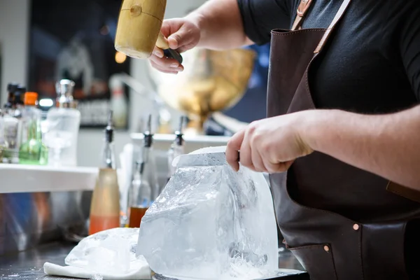 Barkeeper zerkleinert Eis mit Holzhammer und Metallmesser. — Stockfoto