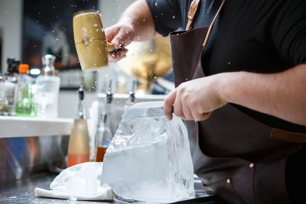 Barman mannually ledová tříšť s dřevěnými kladivo a kovový nůž. — Stock fotografie