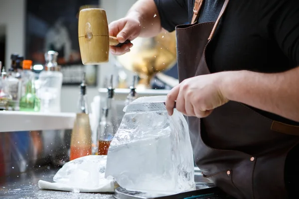 Barman mannually ledová tříšť s dřevěnými kladivo a kovový nůž. — Stock fotografie