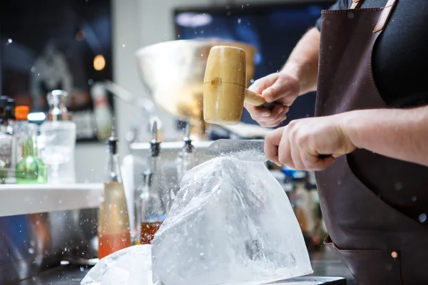 Barman mannually ledová tříšť s dřevěnými kladivo a kovový nůž. — Stock fotografie