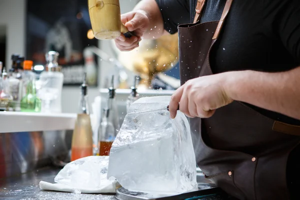 Barman mannually ledová tříšť s dřevěnými kladivo a kovový nůž. — Stock fotografie