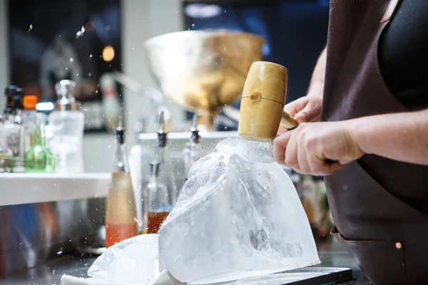 Barkeeper zerkleinert Eis mit Holzhammer und Metallmesser. — Stockfoto