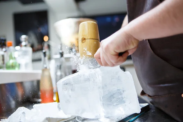 Barman mannually ledová tříšť s dřevěnými kladivo a kovový nůž. — Stock fotografie