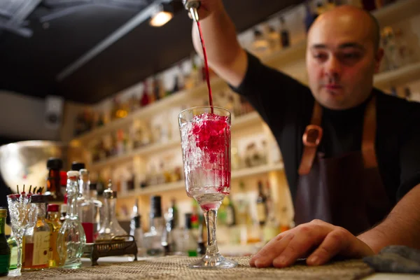 Barman nalévá červené koktejl do sklenky v baru — Stock fotografie