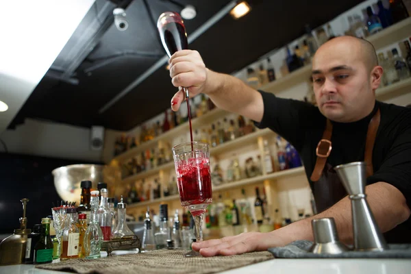 Barman nalévá červené koktejl do sklenky v baru — Stock fotografie