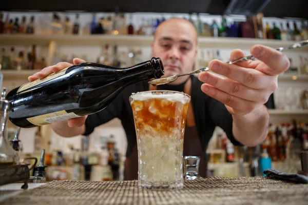 Cantinero vertiendo cóctel en el vaso en el bar — Foto de Stock