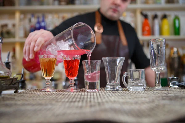 Бармен наливає різні алкоголю напій у невеликих склянки на бар — стокове фото
