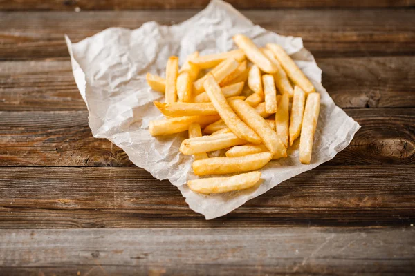 Batatas fritas na mesa de madeira. — Fotografia de Stock