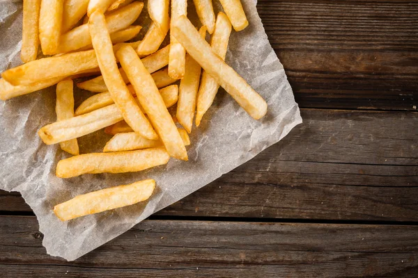 Batatas fritas na mesa de madeira. — Fotografia de Stock