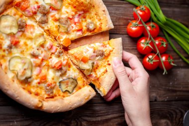 El malzeme çekme lezzetli dilim pizza ahşap masanın üzerinde yatan