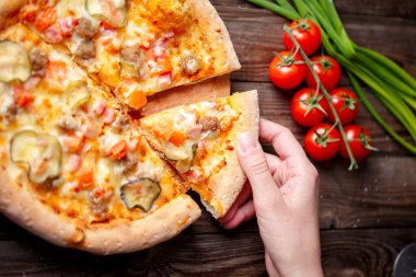 El malzeme çekme lezzetli dilim pizza ahşap masanın üzerinde yatan