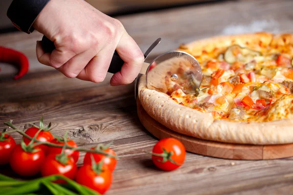 Krojenie świeżej pizzy z rolki nóż. — Zdjęcie stockowe