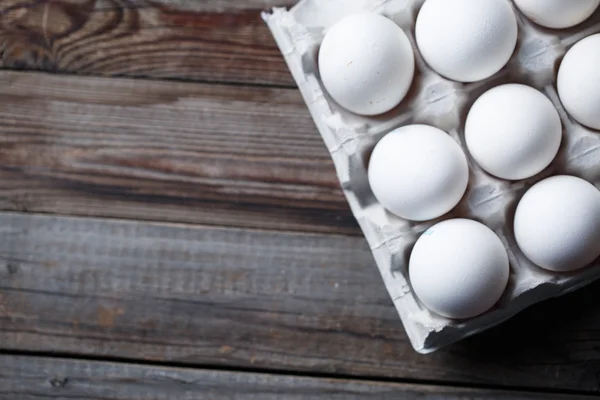 Białe jaja na wiejskim drewnianym stole — Zdjęcie stockowe