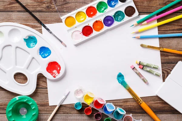 Papier, aquarellen, verf borstel en wat kunst spullen op houten tafel — Stockfoto