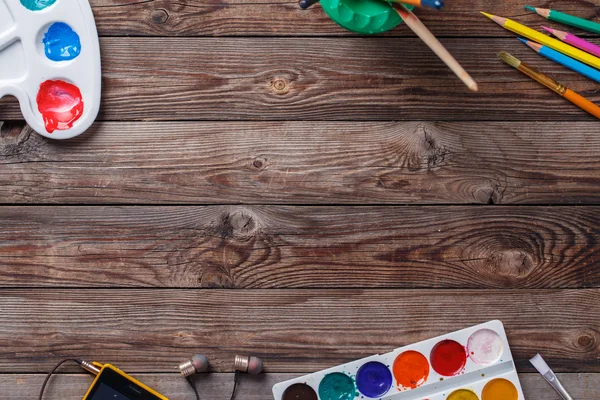 Papír, akvarely, štětec a nějaké umělecké věci na dřevěném stole — Stock fotografie