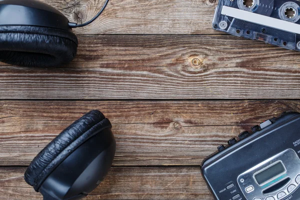 Cassettebandjes, cassettespeler en koptelefoon over houten tafel. bovenaanzicht. — Stockfoto