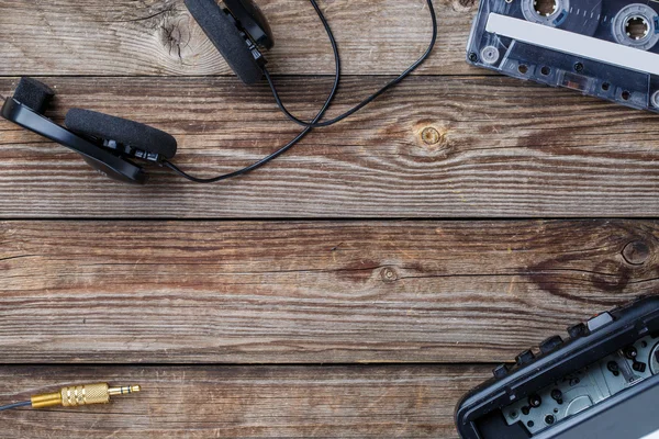 Magnetofonové pásky, kazetové přehrávače a sluchátka přes dřevěný stůl. pohled shora. — Stock fotografie