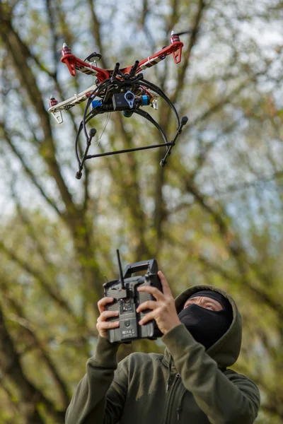 Maskierter Mann bedient Drohne mit Fernbedienung. — Stockfoto