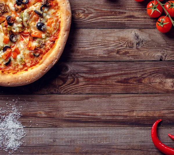 Pizza italiana con pomodori su un tavolo di legno, vista dall'alto. — Foto Stock